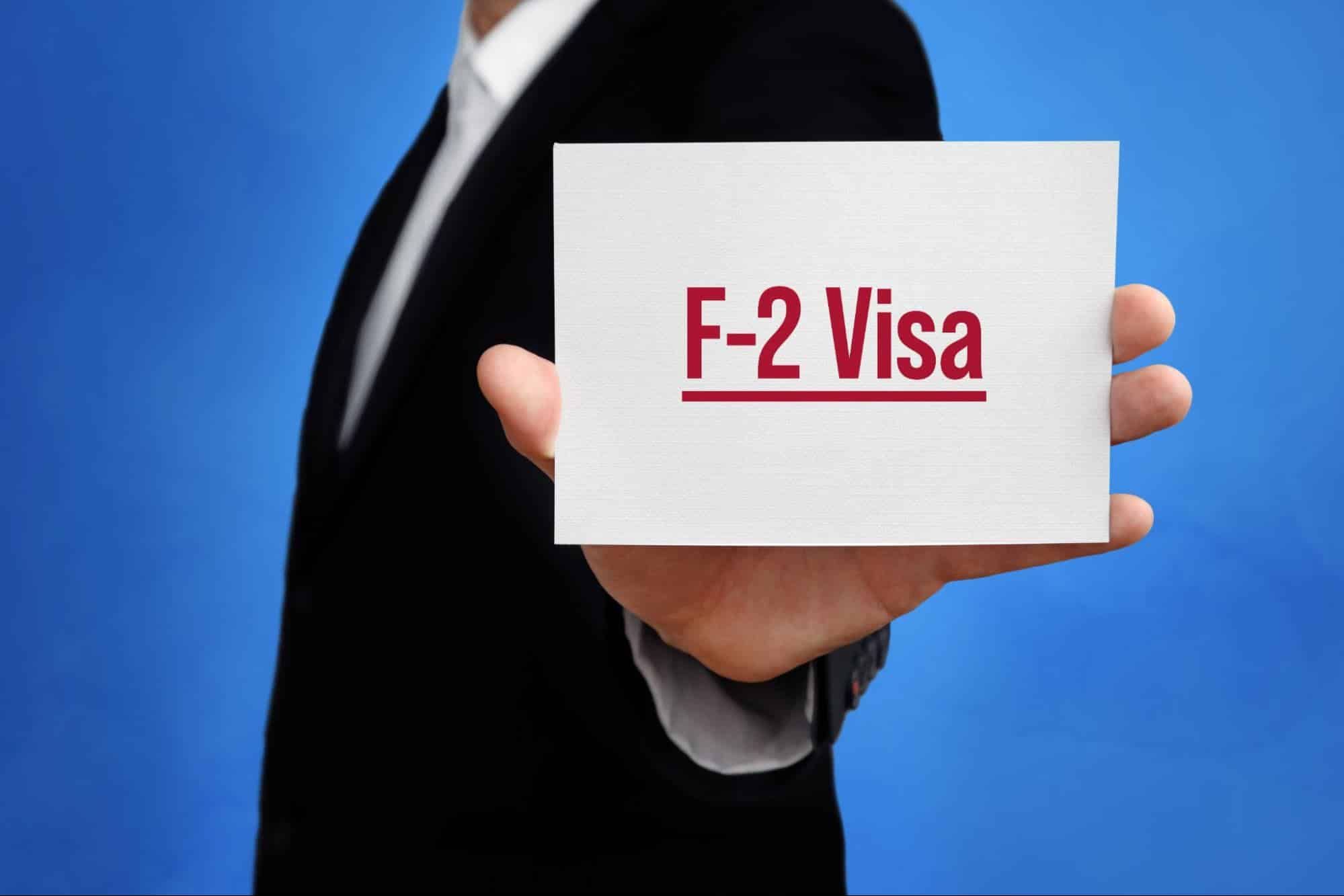 homem segurando folha escrito "F-2 Visa"