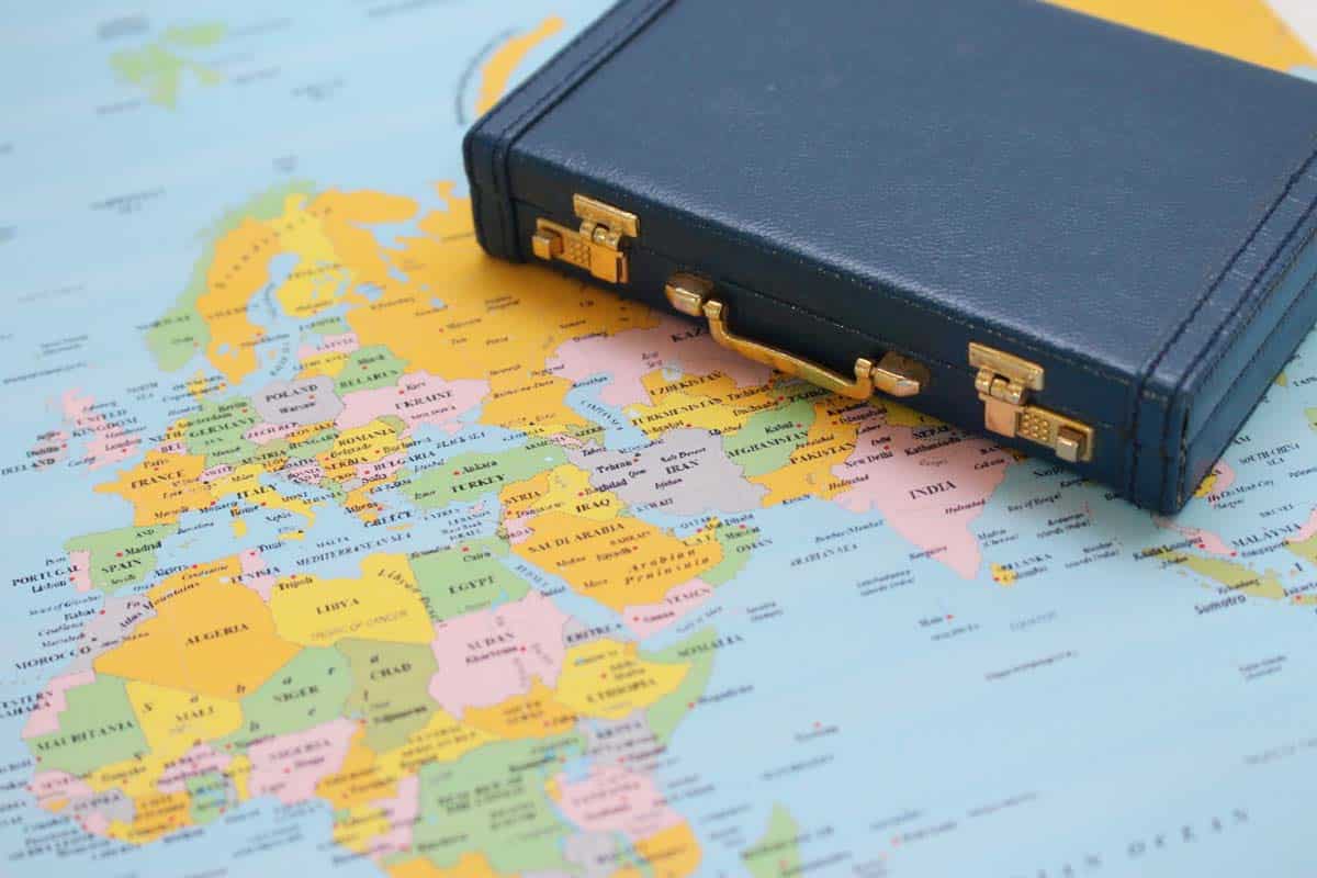 A gold-clasped briefcase on top of a colorful world map