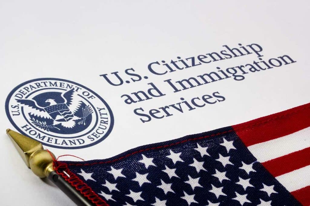Uma pequena bandeira americana em cima de um papel timbrado do U.S. Citizenship and Immigration Services (Serviços de Cidadania e Imigração dos EUA)