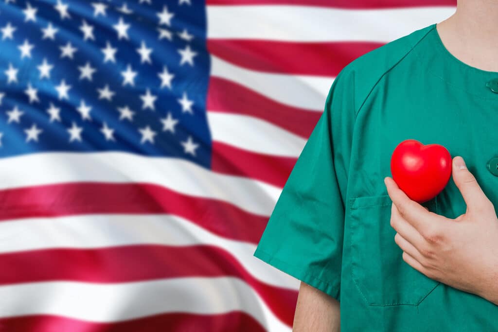 Médico com a bandeira dos Estados Unidos atrás representando como ser medico nos eua